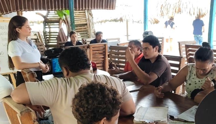 Contratista de Corpamag junto a comunidad reunido en una mesa dictando charla
